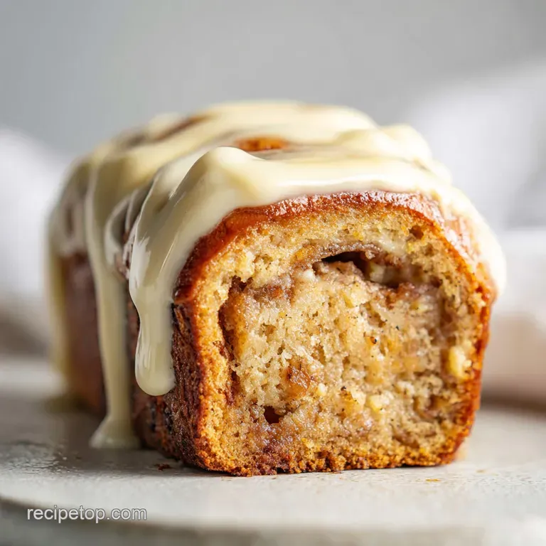 Elegant banana bread cinnamon roll plated with powdered sugar dusting. Soft, light, and warm hues create comforting, sweet...
