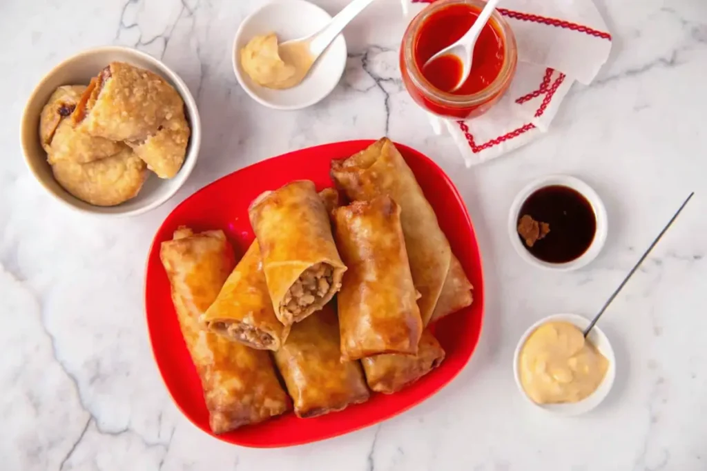 Healthy baked egg rolls on a white platter with dipping sauces