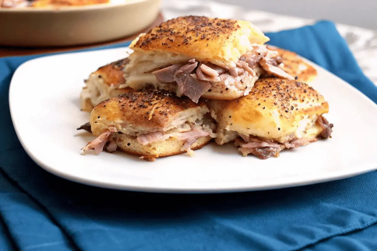 A close-up of a half-eaten roast beef slider, showing the tender beef, melted cheese, and fluffy roll.