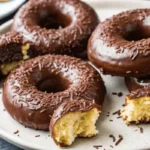 Freshly baked chocolate cake donuts with glaze and toppings.